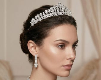 May include: A silver-toned tiara featuring a symmetrical arrangement of clear, faceted crystals in teardrop and marquise shapes, paired with matching drop earrings and a necklace composed of rectangular and teardrop-shaped crystals.
