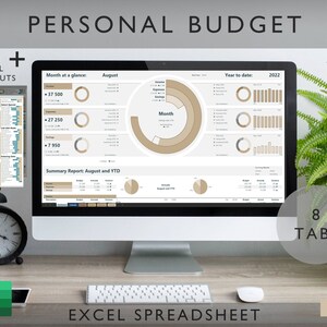 May include: A desktop setup featuring a computer screen displaying a personal budget spreadsheet. The screen shows financial data with charts and graphs. The words "PERSONAL BUDGET" and "EXCEL SPREADSHEET" are displayed. A printout of Excel shortcuts is also visible.