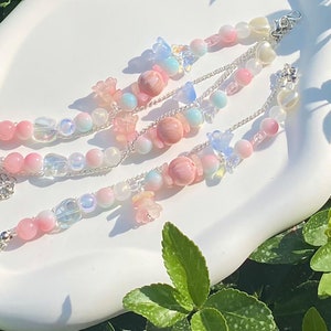 May include: Three layered bracelets with pink, blue, and white beads, charms, and silver chain links.