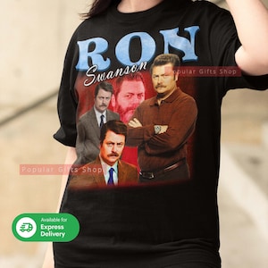 May include: Black t-shirt with a collage of images of Ron Swanson and the name "RON Swanson" in blue text. The shirt has a vintage style with a red background and the words "Popular Gifts Shop" printed on it.