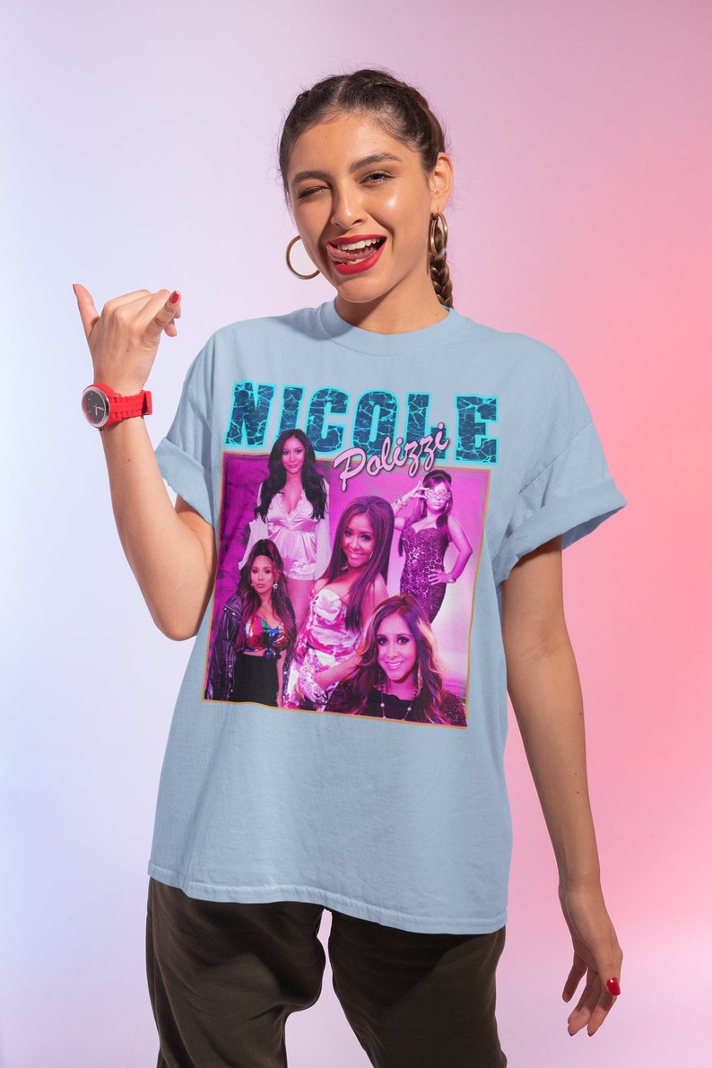 May include: A light blue t-shirt with a graphic print of a collage of women's faces and the text "Nicole Polizzi" in pink and blue letters.