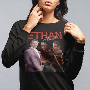 May include: Black sweatshirt with a graphic print of Ethan Hawke and the text "Ethan Hawke" in red.