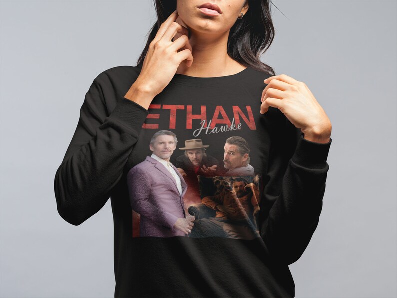 May include: Black sweatshirt with a graphic print of Ethan Hawke and the text "Ethan Hawke" in red.