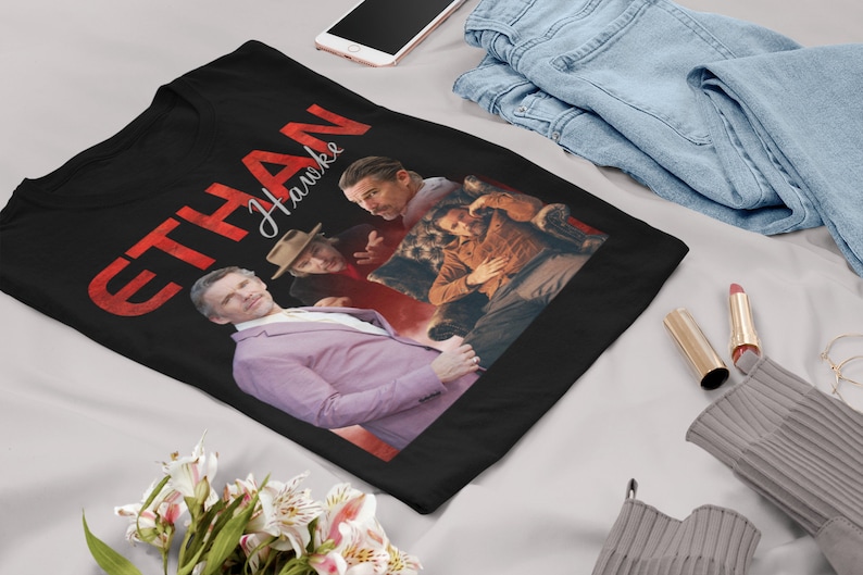 May include: Black t-shirt with a red graphic that says "ETHAN HAWKE" in a bold font. The graphic also features three images of Ethan Hawke in different poses.