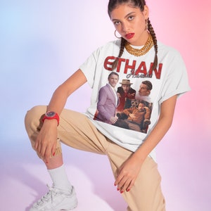 May include: A white t-shirt with a red graphic print of Ethan Hawke. The graphic features a collage of four images of Ethan Hawke in different poses. The text "Ethan Hawke" is printed in red letters above the collage.