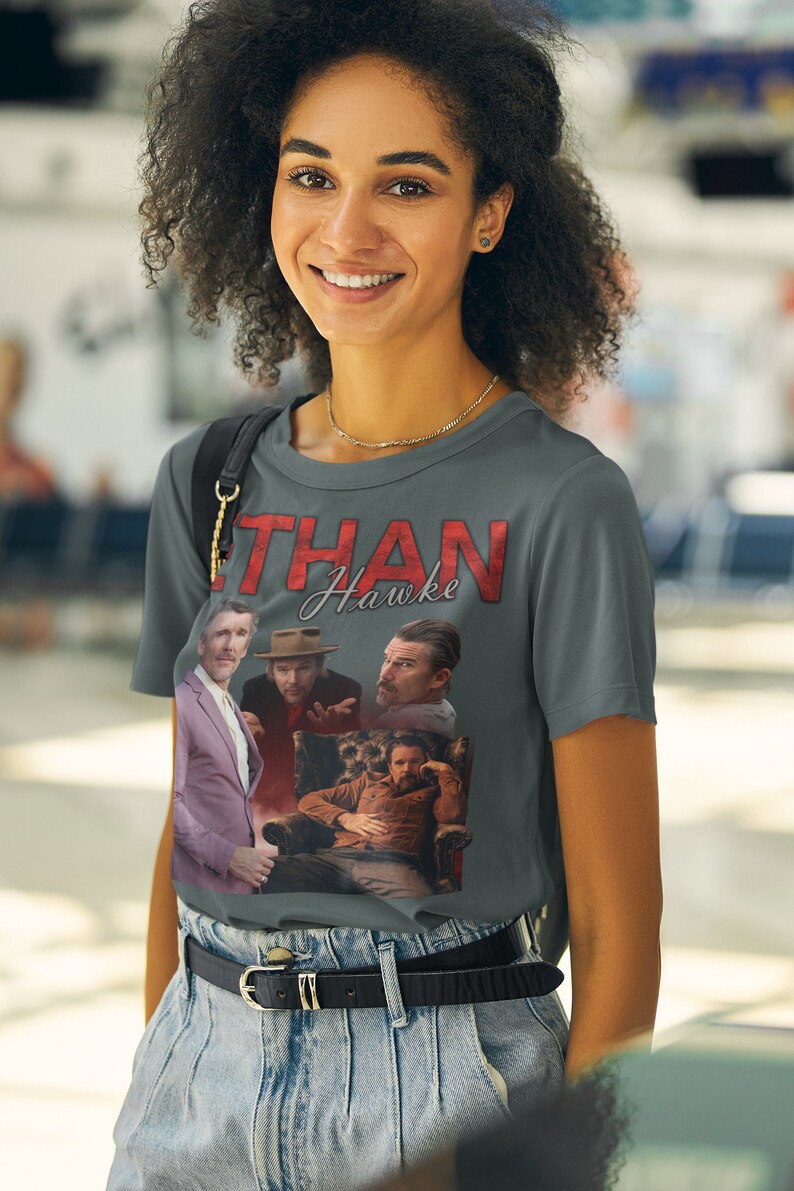 May include: A gray t-shirt with a collage of images of Ethan Hawke. The text "Ethan Hawke" is printed in red on the shirt.