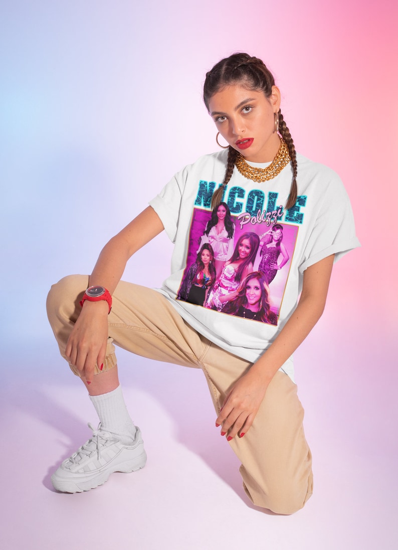 May include: A white t-shirt with a graphic print of a group of women with the text "Nicole Polizzi" in blue and pink.