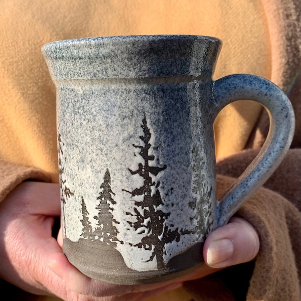 Forest silhouette mug. 12 oz dark brown stoneware mug with hand waxed silhouette pines on a white and blue glaze