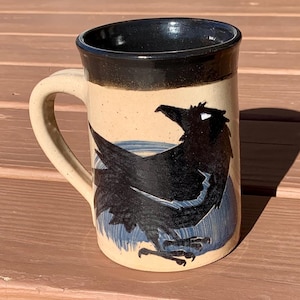 Taza de cuervo. Taza hecha a mano de 16 oz con diseño de cuervo. Pincelada de merluza azul y cuervo negro sobre cerámica. Esmalte transparente en el exterior, negro en el interior.