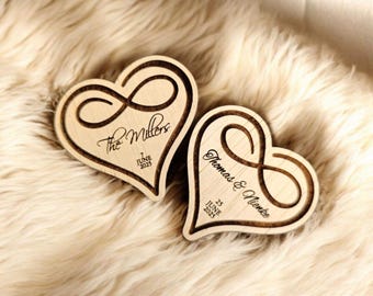 May include: Two wooden heart-shaped ornaments with an infinity symbol engraved on each. The first heart says "The Millers" and "7 June 2023". The second heart says "Thomas & Nicole" and "23 June 2023".