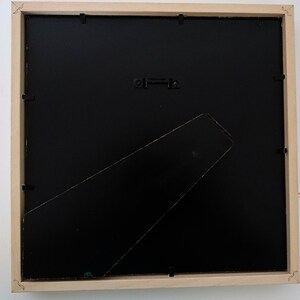 May include: The back of a wooden picture frame with a black mat and a hanging wire.