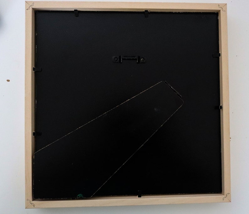 May include: The back of a wooden picture frame with a black mat and a hanging wire.