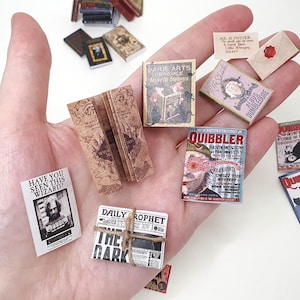 May include: Miniature books and newspapers with various titles, including "The Quibbler" and "Daily Prophet." The collection features a wanted poster with the text "Have you seen this wizard?" and a book titled "Dark Arts Obplace."