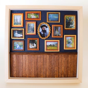 May include: A miniature wooden wall display with a dark blue background and a wood-paneled lower section. The wall is decorated with 11 framed pictures, including a portrait of a man with a beard, landscapes, and still lifes.