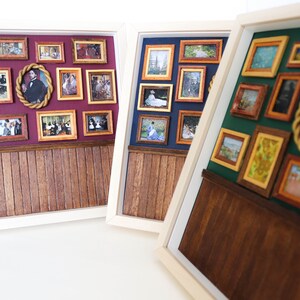 May include: Three white picture frames with wood paneling at the bottom. Each frame contains a gallery wall of miniature framed pictures with various subjects and colors.