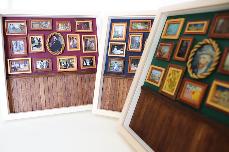 May include: Three white picture frames with wood paneling at the bottom. Each frame contains a gallery wall of miniature framed pictures with various subjects and colors.