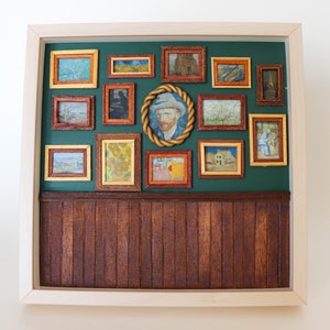 May include: A framed artwork with a green background and a collection of smaller framed paintings inside. The smaller paintings are of various subjects, including landscapes, portraits, and still lifes. The larger frame is made of wood and has a light brown finish.