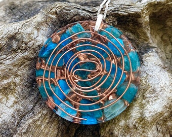 May include: A round pendant necklace with a copper wire spiral design and blue and green crystals embedded in clear resin.