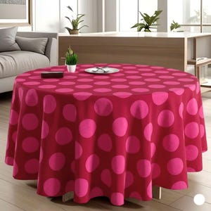 Peut inclure: Une nappe ronde rouge foncé ornée de grands pois roses vifs. La nappe est drapée sur une table ronde, créant un motif visuellement saisissant. Une petite plante, une assiette avec des couverts et une petite boîte sont posées sur la nappe.