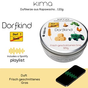 Könnte beinhalten: Eine runde, silberfarbene Duftkerze mit dem Text "Dorfkind" und "Frisch geschnittenes Gras". Der Deckel zeigt Illustrationen eines Traktors, eines Huhns und Weizen. Das Bild enthält auch ein Smartphone mit einer Spotify-Playlist.