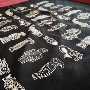 May include: Black fabric with white stylized illustrations of various animals and birds. The fabric has a repeating pattern of the illustrations.