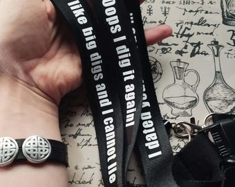 Könnte beinhalten: Zwei schwarze Lanyards mit weißem Text. Der Text auf einem Lanyard lautet "Oops I dig it again!" und der Text auf dem anderen Lanyard lautet "I like big digs and I cannot lie..."