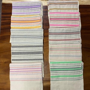 May include: Ten white fabric napkins with different coloured stripes. The stripes are in various colours, including purple, orange, pink, red, black, and green.