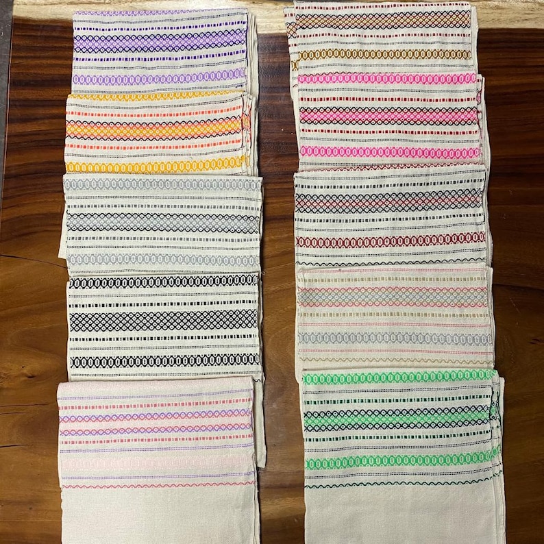 May include: Ten white fabric napkins with different coloured stripes. The stripes are in various colours, including purple, orange, pink, red, black, and green.