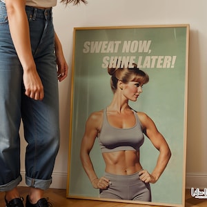 Puede incluir: Un póster vertical enmarcado con fondo verde claro y el texto SWEAT NOW, SHINE LATER! en letras mayúsculas blancas. La imagen muestra a una persona con músculos definidos vistiendo un sujetador deportivo y mallas grises a juego.