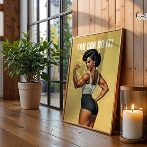 May include: A framed poster featuring a muscular person flexing their arm, wearing a white tank top and black shorts, with the text YOU CAN DO IT! printed in white at the top. The artwork is set against a yellow background with a vintage aesthetic.