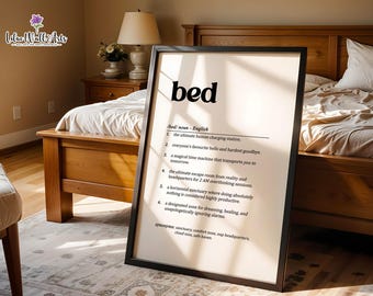 May include: A framed wall art print featuring a dictionary-style definition of the word bed. The text includes the noun definition, six numbered descriptions of a bed, and a list of synonyms, all printed in black ink on a light cream background.