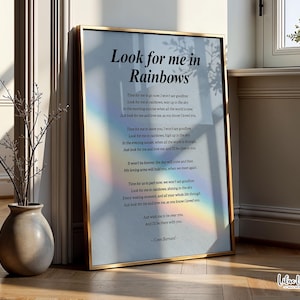 May include: A framed print with the text "Look for me in Rainbows" in a gold frame. The print features a poem with a rainbow effect. A vase with branches and a small potted plant are in the background.