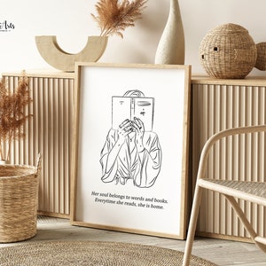 K&ouml;nnte beinhalten: Schwarzwei&szlig;-Linienkunst-Druck einer Person, die ein Buch liest. Der Druck ist gerahmt und h&auml;ngt an einer Wand mit hellem Holzhintergrund. Der Text unter dem Bild lautet "Her soul belongs to words and books. Everytime she reads, she is home."