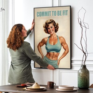 Może przedstawiać: Motywacyjny plakat w stylu vintage przedstawiający kobietę w niebieskim sportowym biustonoszu i spodenkach. Plakat zawiera napis "COMMIT TO BE FIT" w pogrubionych, białych literach.