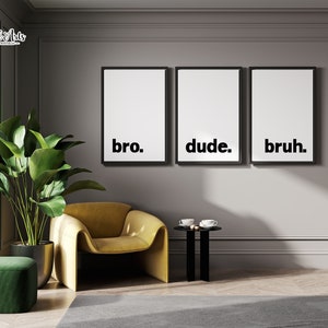 May include: Three black framed prints with white backgrounds and the words "bro." "dude." and "bruh." hanging on a gray wall in a modern living room. A yellow armchair and a green ottoman are in the foreground.