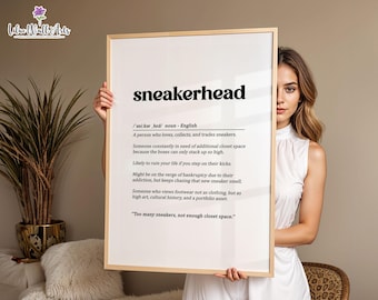 May include: A rectangular wall art print in a light wood frame featuring the dictionary definition of the word sneakerhead in black text on a white background, including phonetic spelling, noun classification, and descriptive sentences.