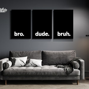May include: Three black framed canvas prints with white text. The text on the prints reads "bro", "dude", and "bruh". The prints are hanging on a dark gray wall above a gray couch.