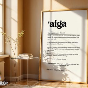 May include: A framed wall art print featuring the word 'aiga' in large black font, followed by its definition as a Samoan noun. The text describes family as a group bound by blood or choice, a sanctuary of love, and a circle of strength.