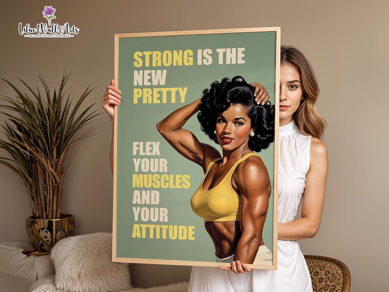 May include: A rectangular framed wall art print featuring a vintage-style illustration of a muscular person with dark curly hair wearing a yellow sports bra. The text reads: STRONG IS THE NEW PRETTY, FLEX YOUR MUSCLES AND YOUR ATTITUDE in yellow.