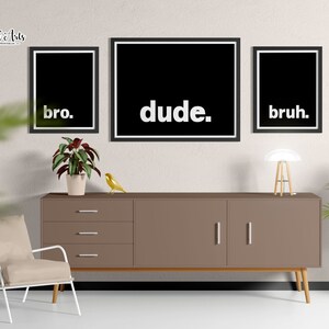 May include: Three black framed prints with white text on a white wall. The prints read "bro." "dude." and "bruh."