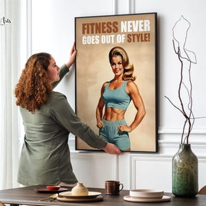 Op de afbeelding: Een poster in vintage stijl met een vrouw in een blauwe fitness outfit. De poster heeft de tekst "Fitness Never Goes Out of Style!" in bruine letters.
