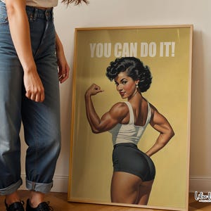 May include: A framed poster featuring a vintage-style illustration of a muscular person flexing their arm, wearing a white tank top and black shorts. The text YOU CAN DO IT! is printed in white at the top against a muted yellow background.