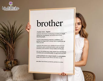 May include: A rectangular wall art print in a light wood frame featuring the dictionary-style definition of the word brother in black text on a white background, including phonetic spelling and descriptive phrases about the role of a brother.
