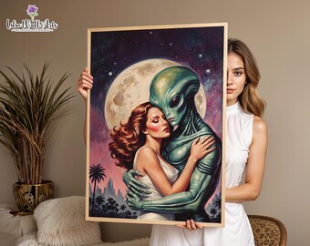 May include: A framed rectangular wall art print featuring a romantic illustration of a person with long wavy brown hair in a white dress embracing a green extraterrestrial being. The background depicts a large full moon, a starry night sky, and silhouettes of palm trees.
