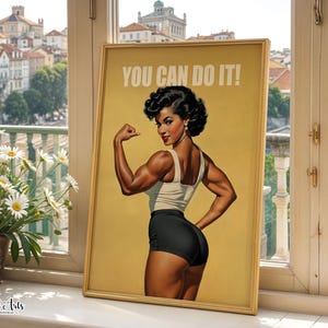May include: A framed poster featuring a vintage-style illustration of a person with dark hair flexing their arm muscles. The person wears a light-colored tank top and black shorts. The text YOU CAN DO IT! is printed in white at the top of the poster.