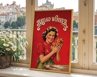 May include: A framed poster featuring a smiling person in a red shirt and green apron holding a braided loaf of bread. The text BREAD WINNER is printed in large white letters at the top. A knife rests on a wooden table in the foreground.