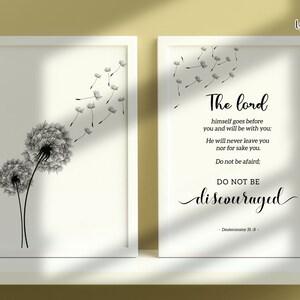 May include: A white framed print featuring a black and white illustration of two dandelions with seeds blowing in the wind. The print also includes a quote from Deuteronomy 31:8: "The Lord himself goes before you and will be with you: He will never leave you nor forsake you. Do not be afraid; DO NOT BE discouraged."