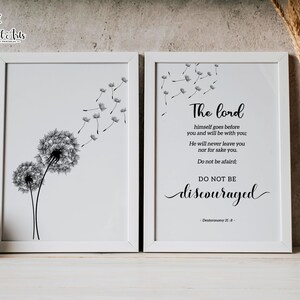 May include: Two black and white prints in white frames. The left print features two dandelion seeds with seeds blowing in the wind. The right print features a bible verse from Deuteronomy 31:8, "The Lord himself goes before you and will be with you: He will never leave you nor forsake you. Do not be afraid; do not be discouraged."