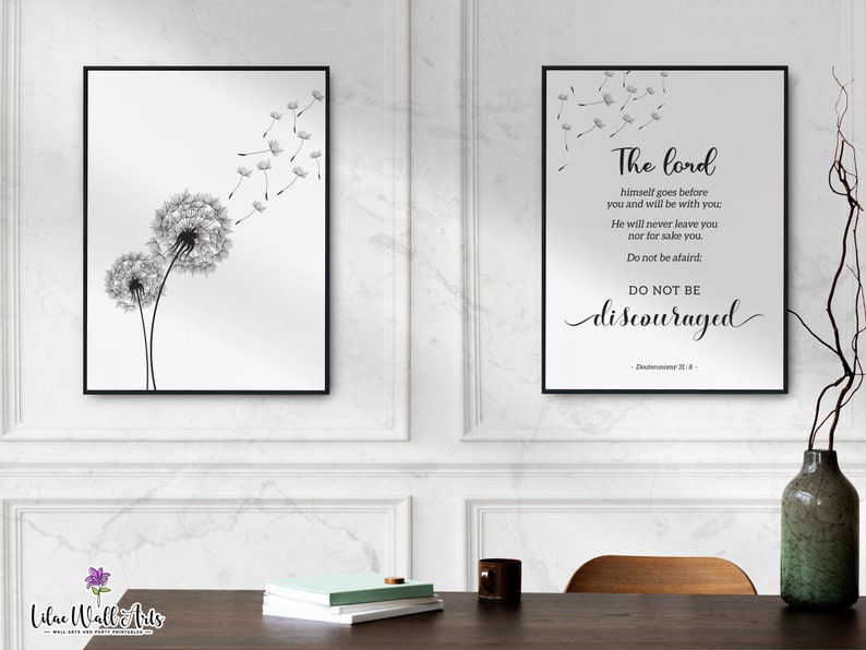 May include: Two black and white framed prints featuring a dandelion design. The print on the left shows two dandelions with seeds blowing in the wind. The print on the right has a quote from Deuteronomy 31:8, "The Lord himself goes before you and will be with you. He will never leave you nor forsake you. Do not be afraid. Do not be discouraged."