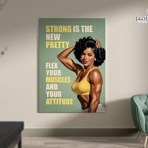 May include: A rectangular wall art print featuring a muscular individual with dark curly hair wearing a yellow sports bra. The background is sage green with the text: STRONG IS THE NEW PRETTY, FLEX YOUR MUSCLES AND YOUR ATTITUDE in yellow and white.